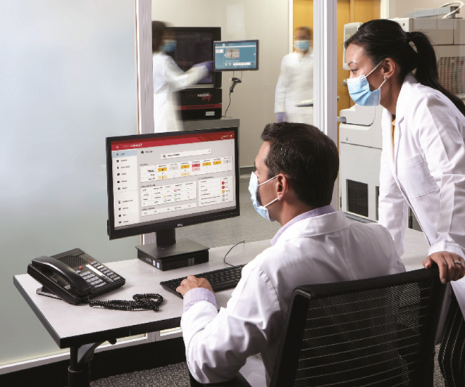 two people in lab coats looking at a computer